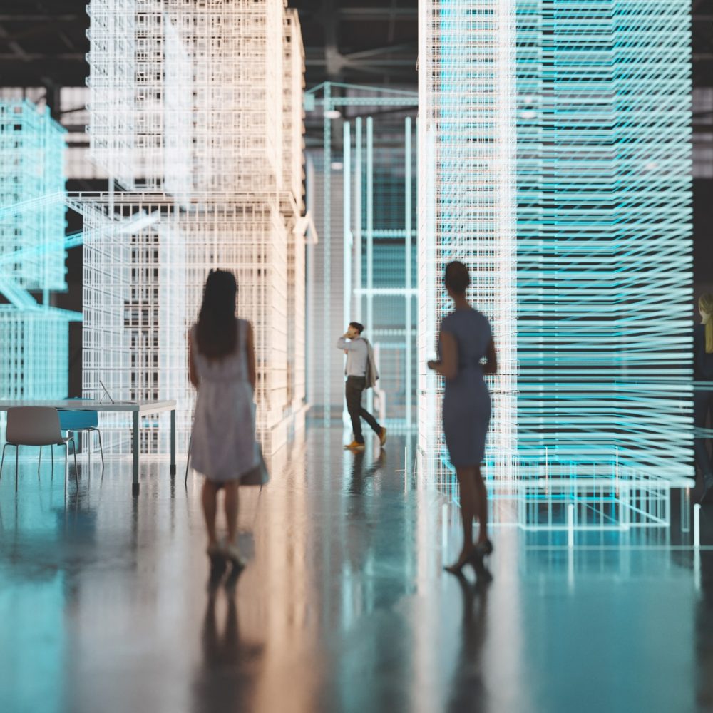 Engineers working in an empty industrial building with augmented reality software simulating a new city block. All items in the scene are 3D